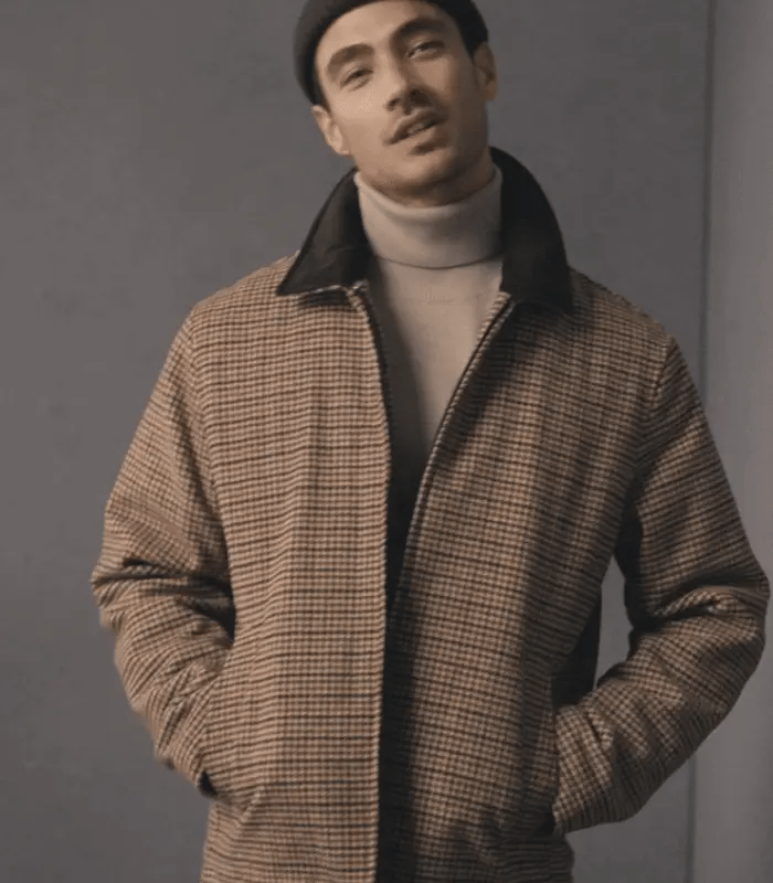 Man wearing a checkered jacket over a turtleneck sweater against a plain background