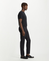 Side view of model wearing Black Men's Slim Tapered Fit Smart 360 Flex Alpha Chino Pants.