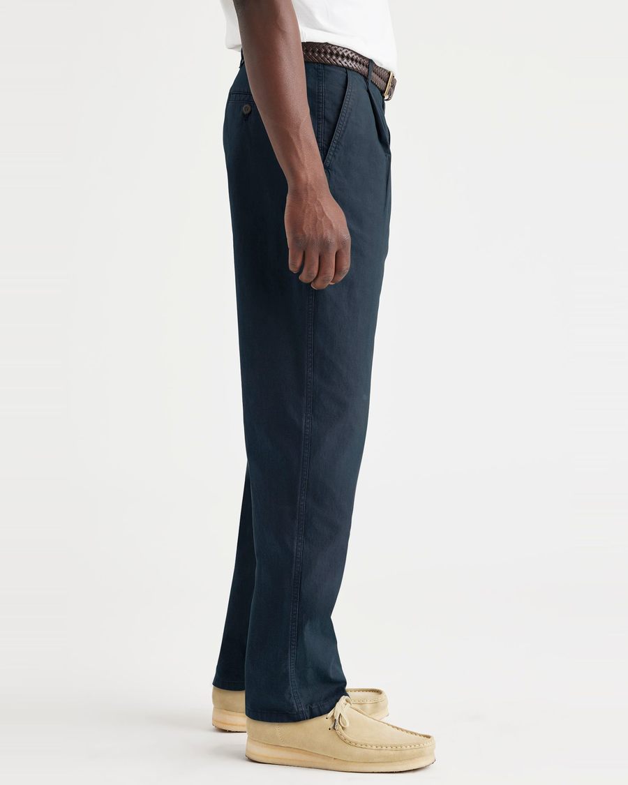 Side view of model wearing Navy Blazer Men's Relaxed Taper Fit Original Pleated Chino Pants.