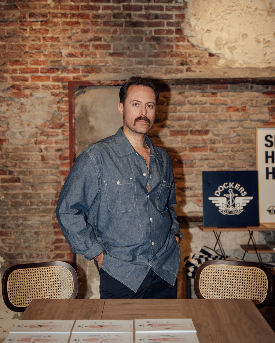 Man standing in a room with a brick wall and wooden furniture