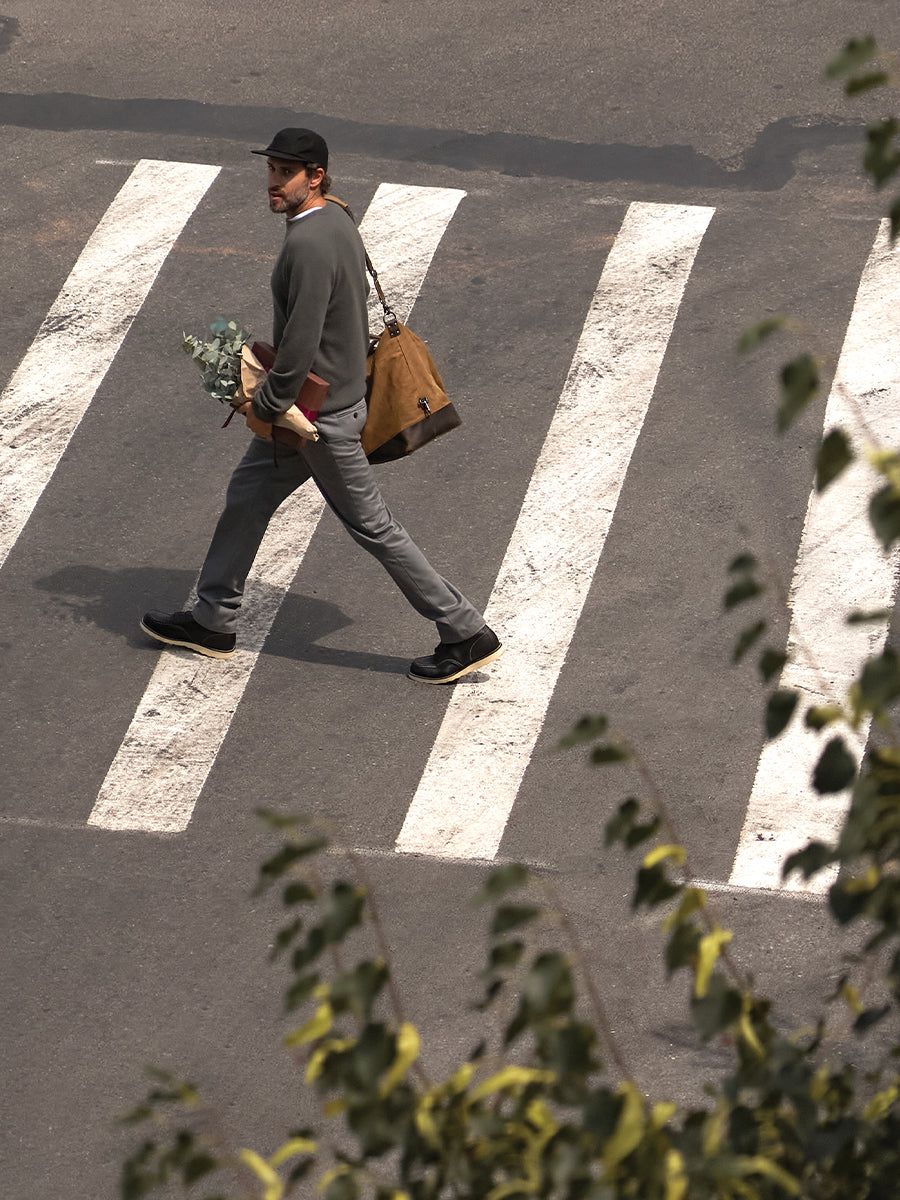 Person walking on a zebra crossing with a bag and skateboard
